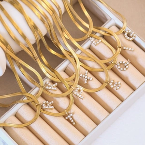 Goldene flache Schlangenkette mit Perlen-Buchstabenanhängern in einer Schmuckschatulle