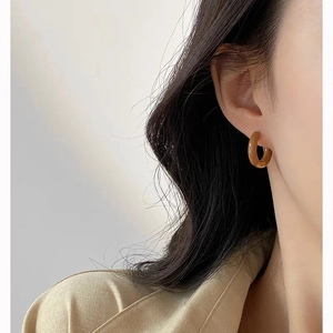 Close-up of caramel resin hoop earrings with glossy finish on a female model