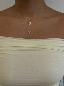Dettaglio di collane a strati in oro 18K con ciondoli a lettera S e Y con cristalli lucidi