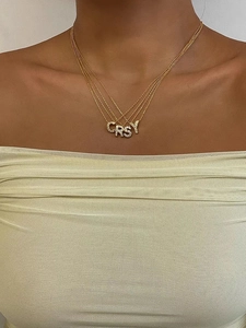 Dettaglio di collane a strati placcate in oro 18K con pendenti a lettere CRSY