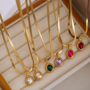 Close-up of golden herringbone chains with oval multicolor zircon pendants in a box