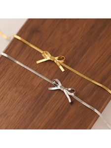 Detail von goldenen und silbernen Schlangenketten mit Schleife auf einem Walnussholzständer