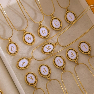 Close-up of gold plated stainless steel letter necklaces with oval lavender pendants