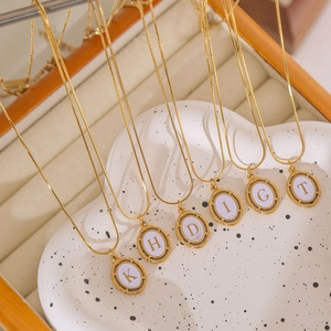 Gold plated stainless steel snake chains with oval letter pendants on a jewelry stand