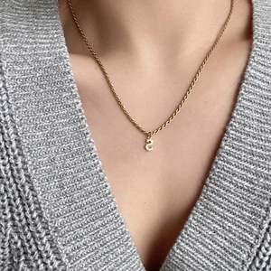 Dettaglio della collana a corda dorata con un ciondolo a lettera S con zirconi scintillanti