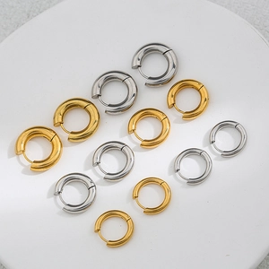 Gold and silver chunky stainless steel hoop earrings in various sizes on marble