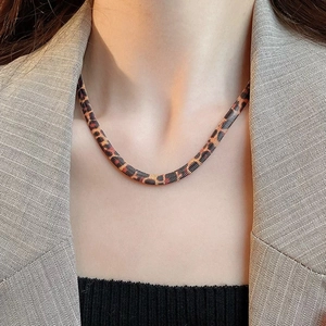 Flat snake bone chain necklace with leopard print finish on chic model's neck