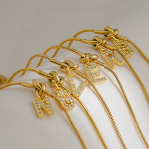Macro-opname van gouden slangenkettingen met met kristallen ingelegde letterhangers