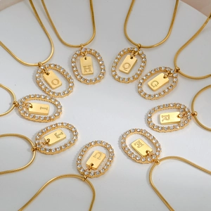 Macro view of gold initial letter pendants with sparkling crystals on snake chain necklaces