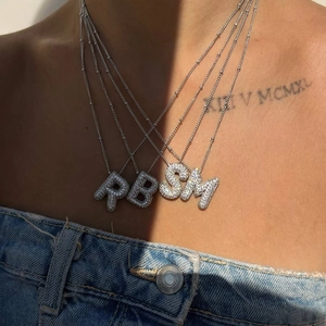 Iced out bubble initial necklace featuring micro-paved zircon alphabet pendants on a model