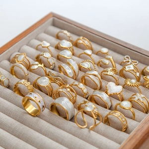 Collection de bagues tournesol et géométriques en acier doré sur plateau à bijoux gris