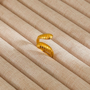 Macro shot of gold-plated spiral texture ring on minimalist linen jewelry holder display