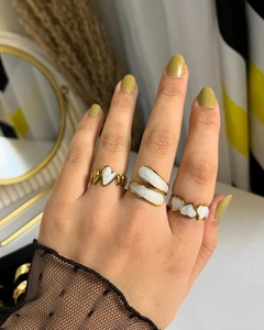 Ensemble de trois bagues cœur en émail blanc et doré porté à la main d'un modèle