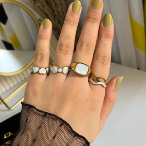 Vue détaillée de bagues dorées superposées avec cœur en émail blanc et motifs géométriques