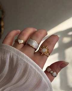 Détail de bagues dorées empilables avec texture marbrée et design de fleur solaire