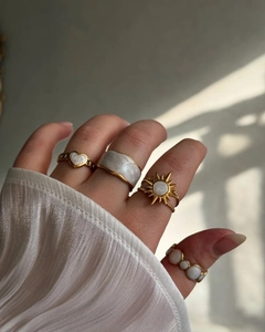 Détail de bagues dorées avec émail blanc et motifs de soleil sertis de pierres