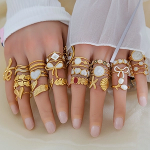 Dettaglio di mani che indossano anelli vintage placcati oro 18K con decorazioni smaltate