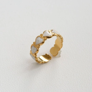 Anillo ajustable de acero inoxidable dorado con una fila de corazones de esmalte blanco