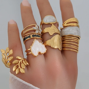 Gros plan d'un ensemble de bagues dorées 18K avec motifs feuilles et papillons sur main
