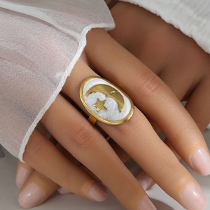 Macro detail of gold moon and star ring with white pearlescent enamel on a model finger