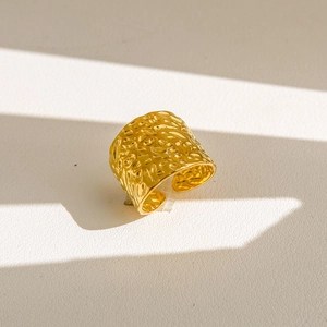 Vue macro d'une bague large dorée avec texture martelée irrégulière et anneau ajustable