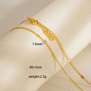 Detailed macro view of 1.6mm golden stainless steel chain with lobster clasp and tag