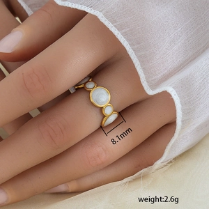 Detalle de anillo geométrico vintage dorado con esmalte blanco sobre encaje fino