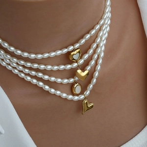 Primo piano della collana di perle a più strati con ciondoli a cuore dorati su modella