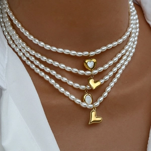 Dettaglio della collana di perle multistrato placcata oro con ciondoli a cuore in conchiglia