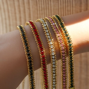 Détail de bracelets tennis dorés avec pierres colorées portés sur le poignet