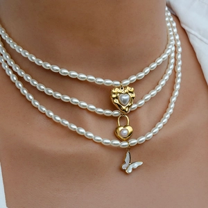 Dettaglio della collana di perle a tre strati con pendenti a cuore dorato e farfalla