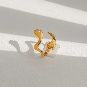 Détail d'une bague mains qui s'enlacent dorée avec finition métallique polie