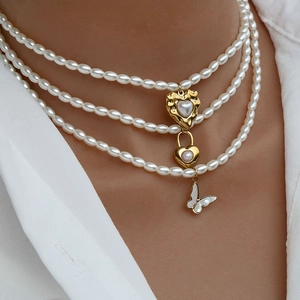 Dettaglio della collana di perle multistrato con ciondoli a cuore dorato e farfalla
