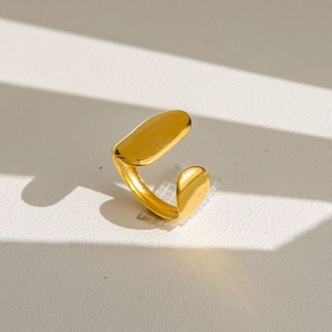 Détail macro d'une bague dorée géométrique ouverte avec finition polie et ombres élégantes