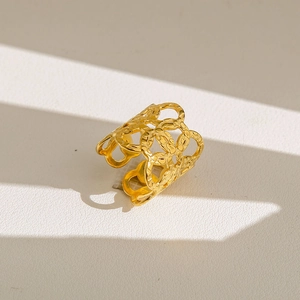 Détail d'une bague large dorée avec motifs ajourés bohèmes et une texture martelée fine