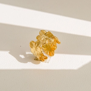 Détail macro d'une bague fleur dorée avec pétales brossés et ombres élégantes