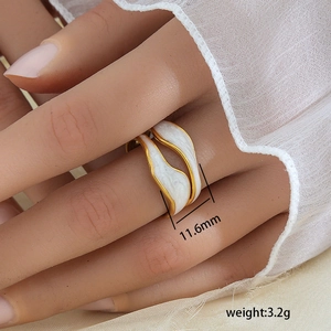 Detalle de anillo ajustable de ondas doradas con esmalte blanco, ancho 11,6 mm y peso 3,2 g