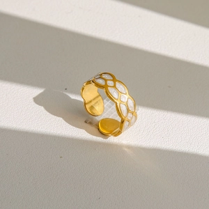 Détail d'une bague dorée réglable avec un motif en treillis de paillettes blanches sur cuir