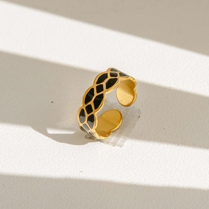 Détail d'une bague fleur dorée avec texture en émail noir et anneau ajustable poli