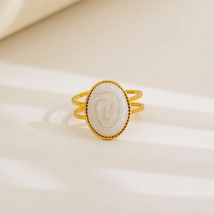 Detail of gold-plated stainless steel ring with white oval embossed spiral texture