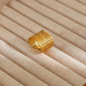 Detailed view of vintage gold hollow woven ring displayed on linen jewelry holder