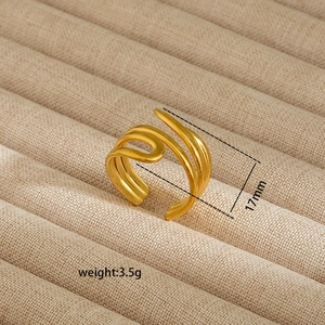 Detailed macro view of gold-plated multi-layer crossover open ring on a beige velvet tray