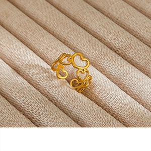 Macro shot of gold vintage enamel pearl ring featuring hollow heart patterns on a velvet tray