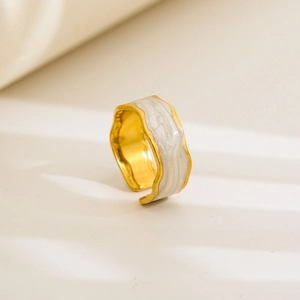 Detailed close-up of golden adjustable ring with white marble enamel finish and wavy edges