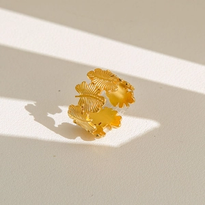 Détail d'une bague ajustable dorée avec motif de feuilles sur fond en cuir