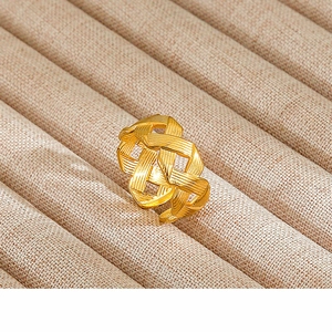 Detail showing the intricate golden woven design and brushed metal texture of the open ring