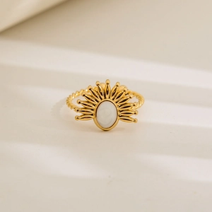 Macro shot of gold sunburst ring with white oval inlay and twisted rope band detail