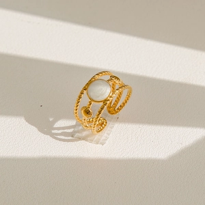 Détail de la bague torsadée dorée avec incrustation de coquillage blanc et ornements