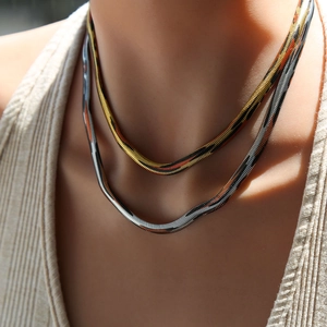 Detalle de collares de cadena de serpiente en capas de oro y plata en el cuello femenino
