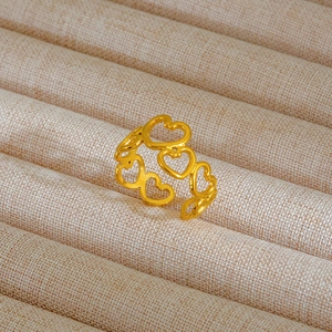 Anello aperto dorato con cuori traforati su un supporto per gioielli in iuta